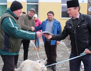 Kuvasz kutyát ad át egy erdélyi gazdának dr. Bilisics Péter (balról) a Pest Vármegyei Polgárőr Szövetség elnöke